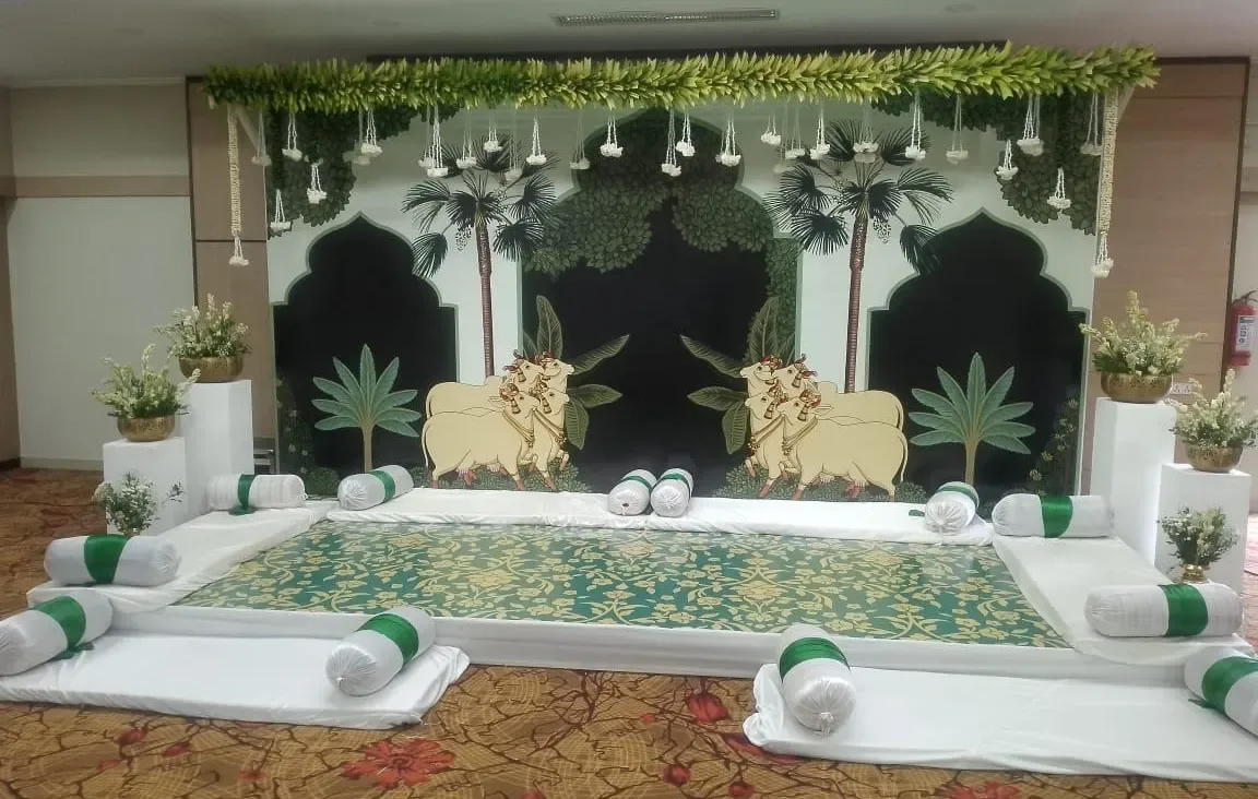 Pichwai-inspired mandap backdrop with green palms and traditional cow motifs for an Indian wedding by Imagine Decorators