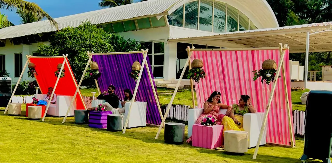 Bright A-frame mehendi lounges in red, purple and pink stripes on a lawn at a Goa wedding by Imagine Decorators