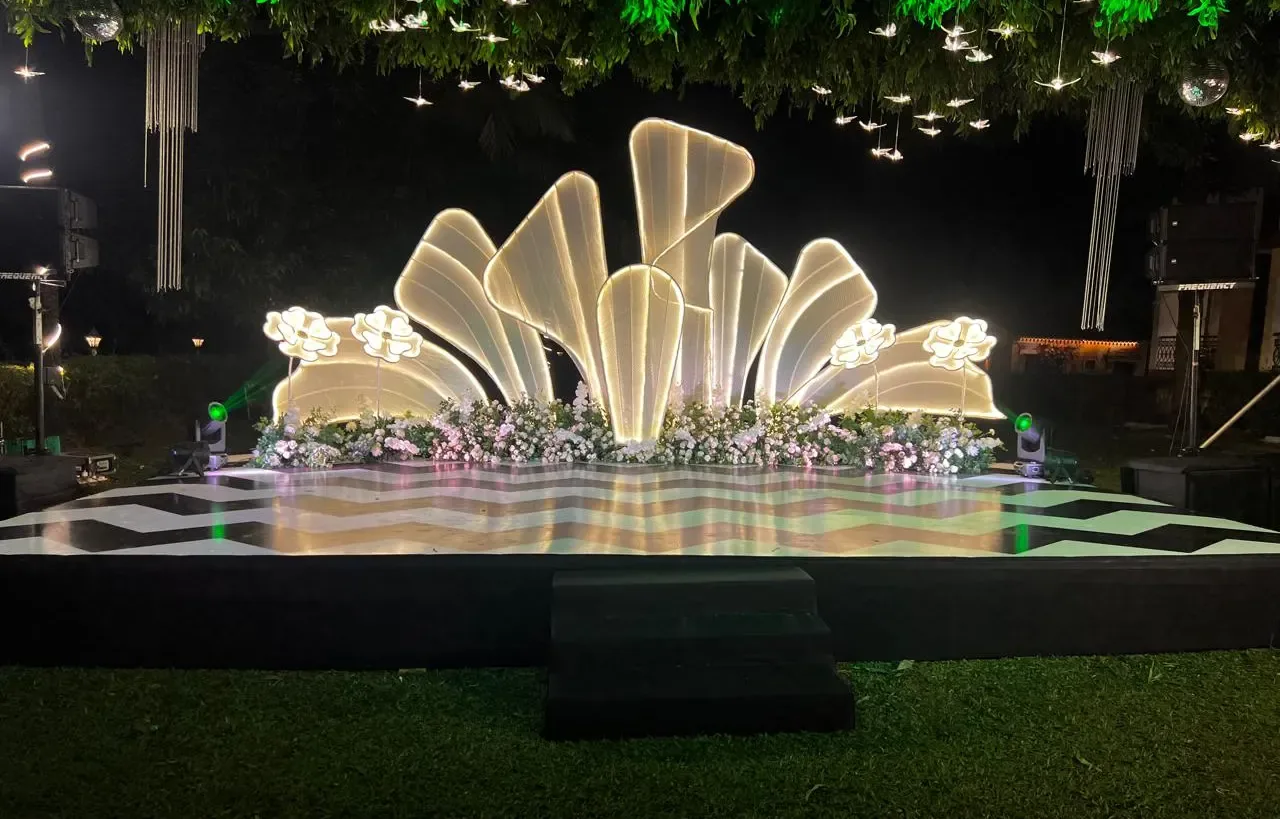 Illuminated white shell stage backdrop with mirror-tiled dance floor for a sangeet by Imagine Decorators