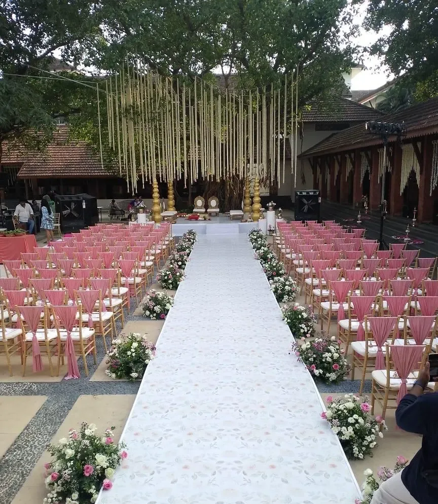 Outdoor wedding aisle with pink chiavari chair sashes, floral runners and hanging garlands by Imagine Decorators