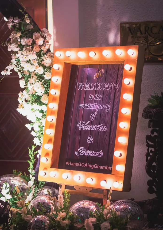 Hollywood-style mirror welcome sign with bulb frame and disco balls for a Goa cocktail party by Imagine Decorators