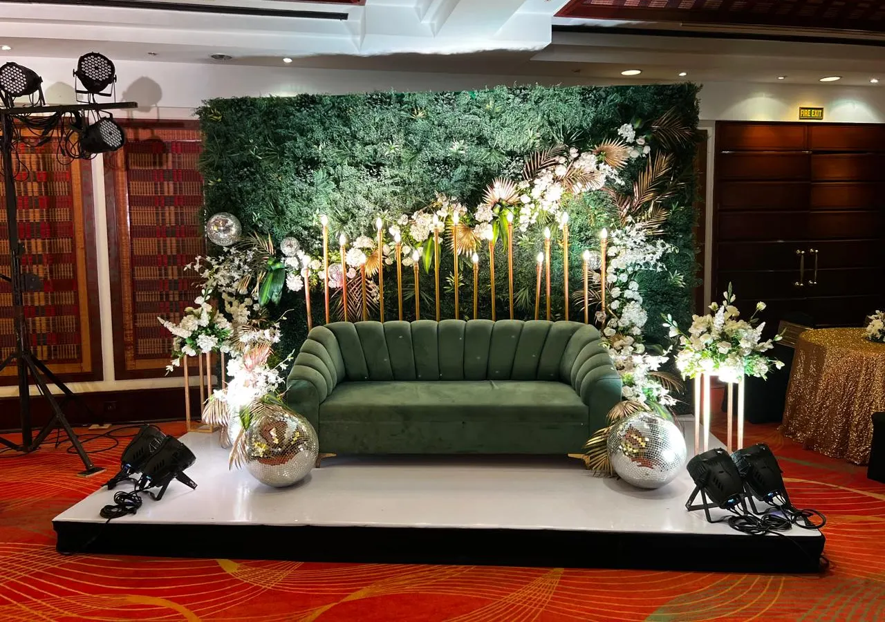 Green velvet sofa stage with disco balls and a vertical garden backdrop for a Goa cocktail party by Imagine Decorators