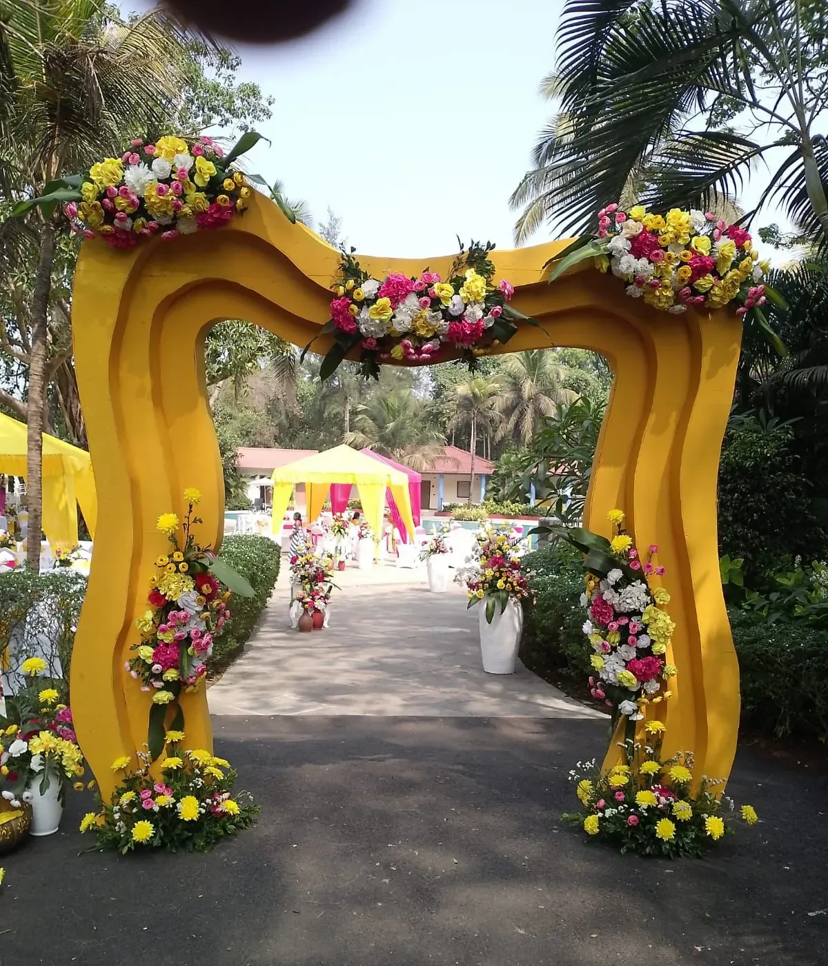 Yellow and pink draped haldi entry gate with marigold garlands and traditional umbrellas in Goa by Imagine Decorators