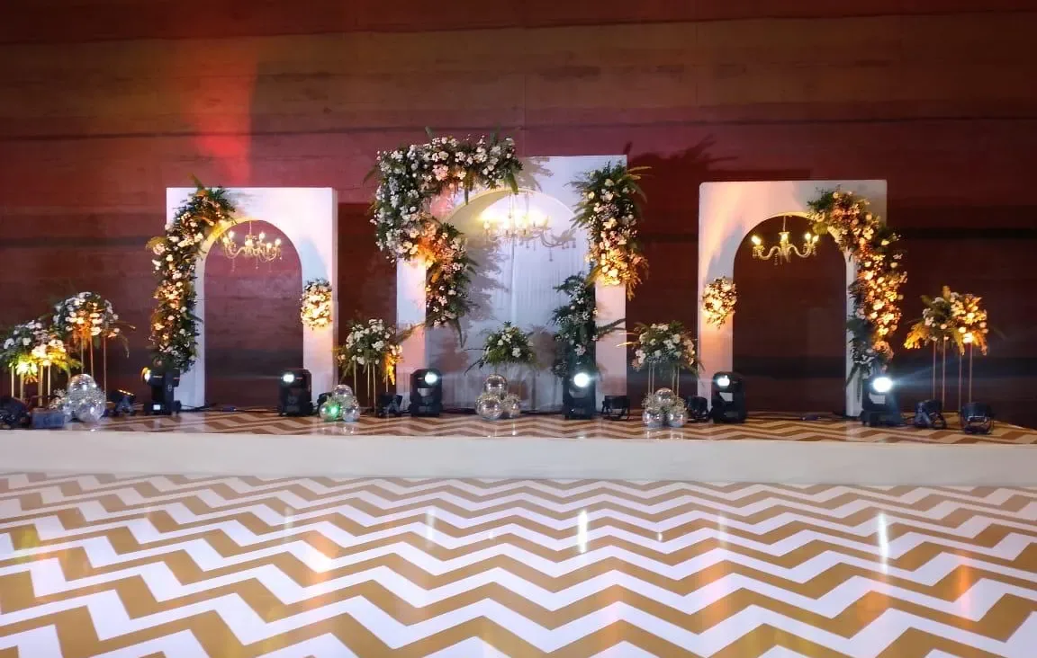 Triple white arches with chandeliers, florals and a gold chevron dance floor at a Goa reception by Imagine Decorators